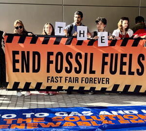 protesters hold a sign that says end fossil fuels