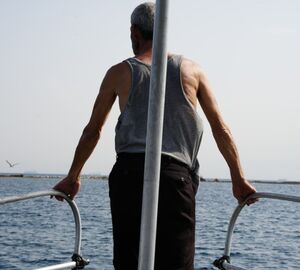 man standing at the top of a boat looking at the sea