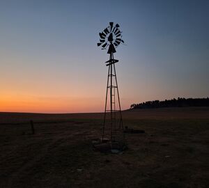 A picture of a windmill at sunset.
