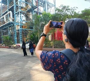 A woman in taking a photograph with her phone of a gas production facility.