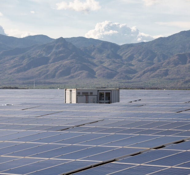 a field of solar panels with mountains in the background