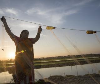 a woman with a fishing net near a pond