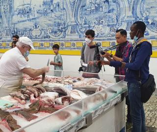 Journalists interviewing a fishmonger at a fish market
