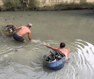Two men with buckets in polluted water