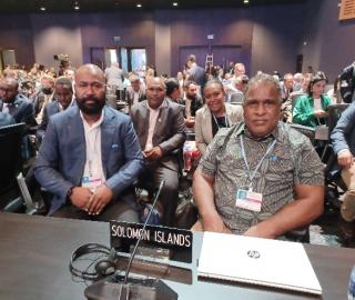members of the solomon islands delegation sitting in a crowded room at COP27