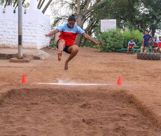 A woman athlete jumps into a pit of sand for training