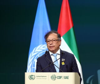 Colombian President Gustavo Petro stands at a podium with the United Nations and United Arab Emirates flags behind him.