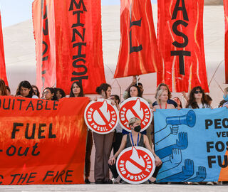 a protest at cop red signs against fossil fuels