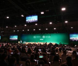 a big auditorium with a green background and a large crowd facing the stage
