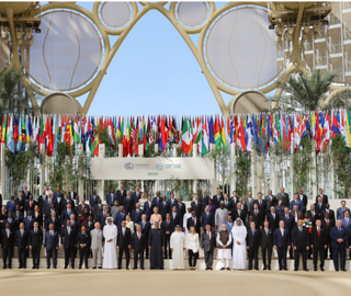 a large group of people standing in front of international flags