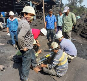 Men in hardhats standing and kneeling at a coal mine.