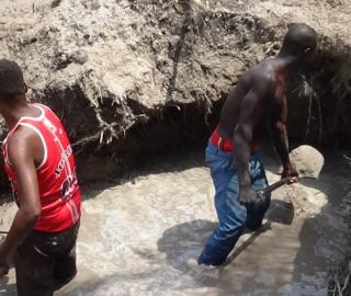 Two young men extracting sand with shovels 