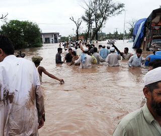 people try to flee a flooded street in Pakistan