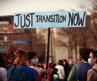 People at a protest holding a 'just transition now' banner 