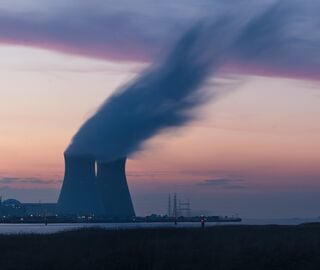 nuclear plant cooling tower emitting smoke at sunset